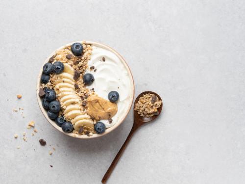 Plantaardige yoghurtbowl met blauwe bessen, banaan, pindakaas & granola